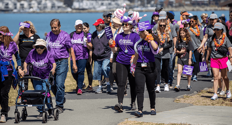 people in purple t-shirts walking on pathway near the shoreline